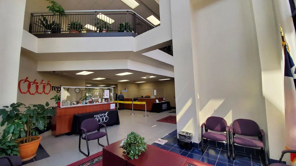 The original employee reception area with a red reception desk, purple seating, and an open upper-level balcony.